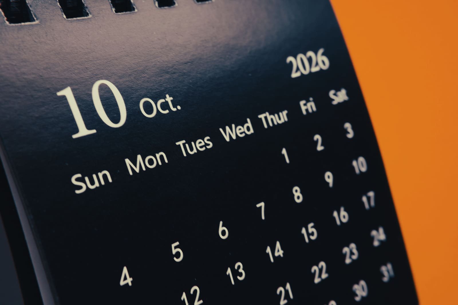 Close view of a desk calendar open to October, the tenth set large at the top of the page