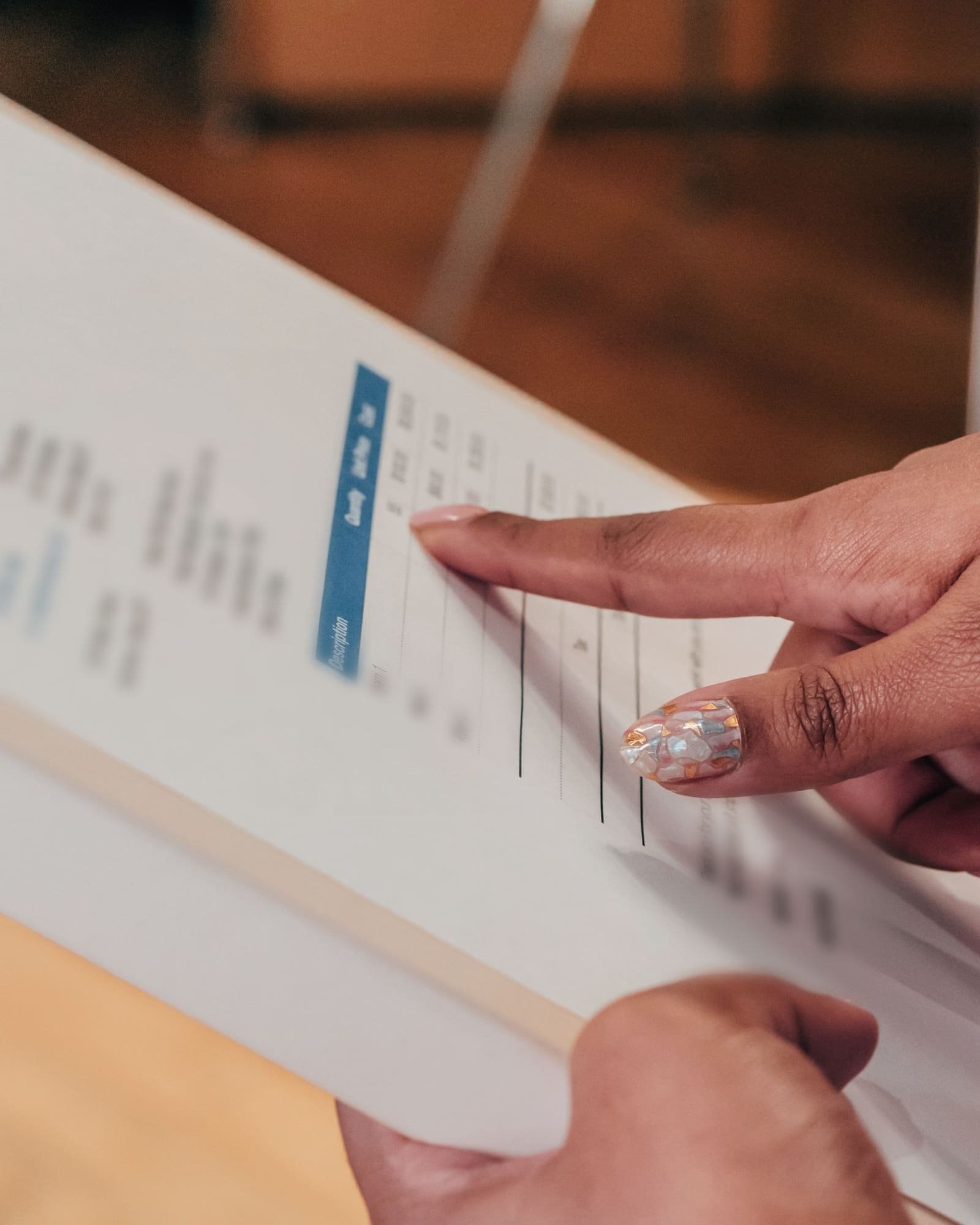 A finger tracing a line on a printed invoice clipped to a board